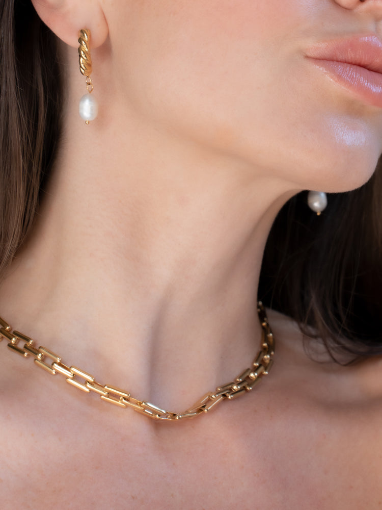 Chunky gold link necklace worn with twisted gold pearl drop earrings